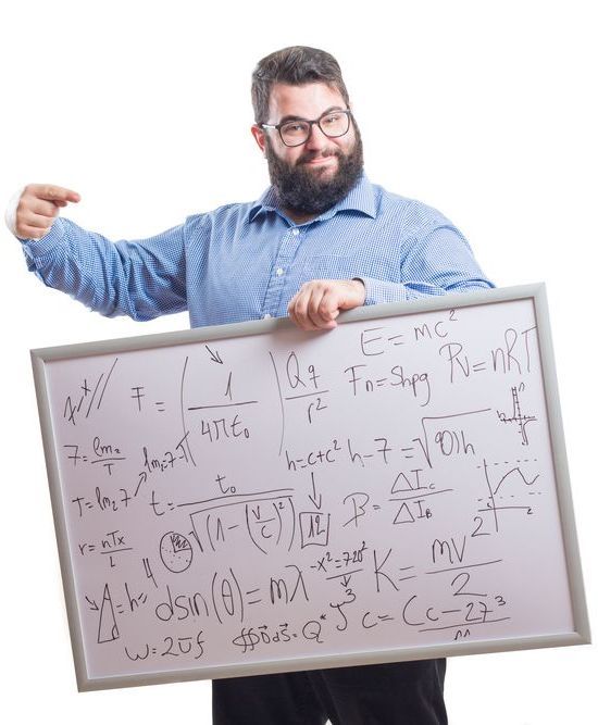Bearded man in blue shirt pointing at a whiteboard covered with equations and graphs