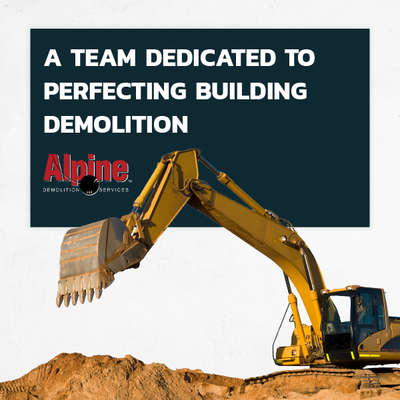 Yellow excavator demolishing a dirt mound with a sign reading “A team dedicated to perfecting building demolition.”