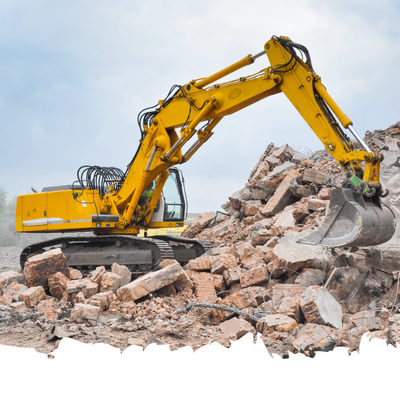 Yellow excavator demolishing a rubble pile at a construction site
