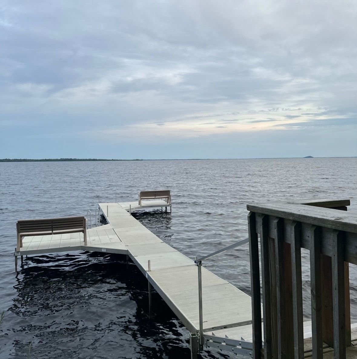 Wooden dock extending into a calm lake under a cloudy sky at dusk