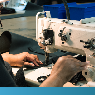 Hands guiding fabric through a sewing machine in a workshop