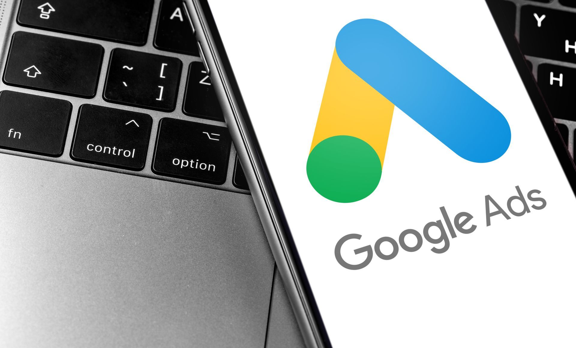 Laptop keyboard beside phone displaying Google Ads logo and text