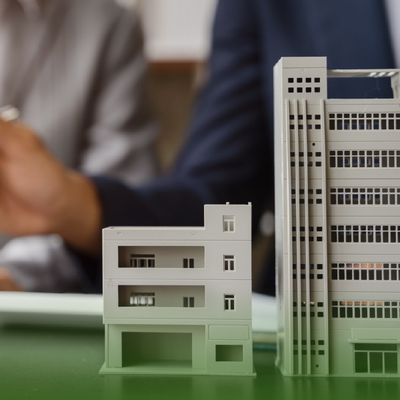 Scale model buildings on a green surface with a blurred person in the background
