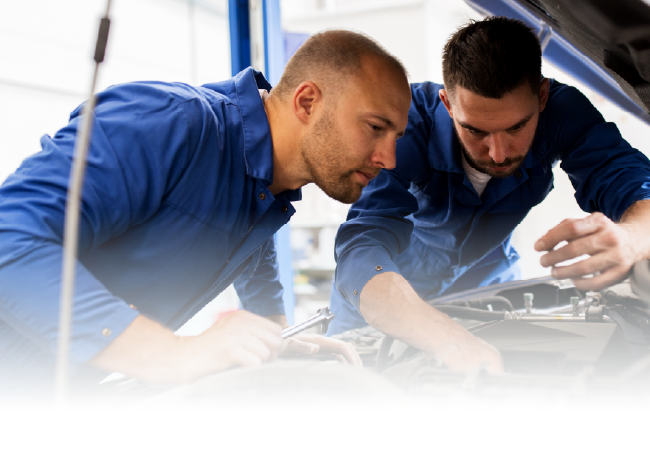 Two technicians in blue uniforms inspecting equipment together in a bright workspace