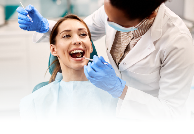 Dentist examining a smiling patient’s teeth with blue gloves and tools in a bright clinic