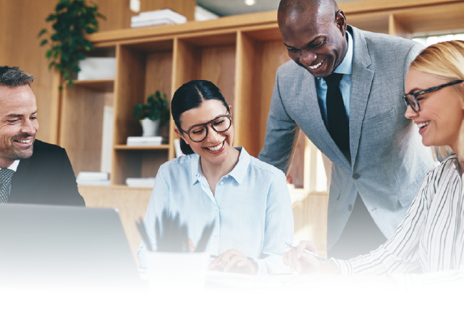 Colleagues smiling and collaborating around a laptop in a bright office