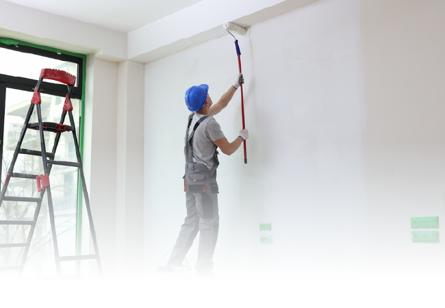Person painting a white wall with a roller beside a stepladder in a bright room