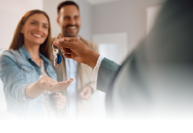 Handing over house keys to a smiling couple in a bright home interior