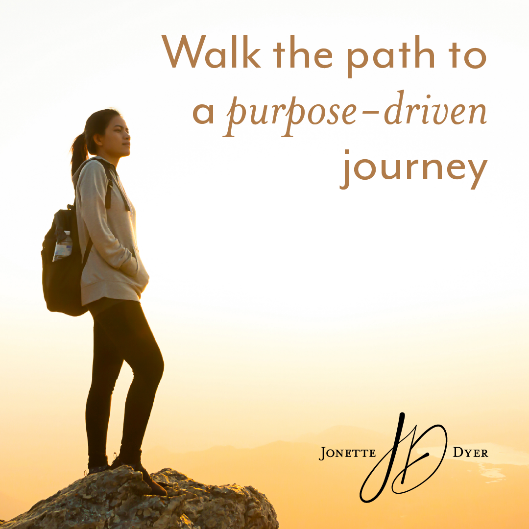Woman with backpack standing on a rocky peak at sunrise beside text: “Walk the path to a purpose-driven journey”