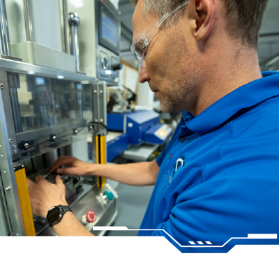 Worker in blue shirt inspecting machinery on a factory line