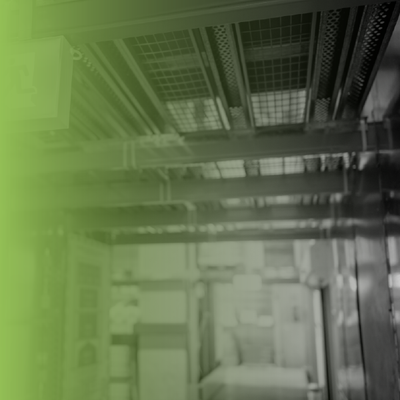 Green-tinted industrial interior with metal beams, ceiling grates, and bright light in the background