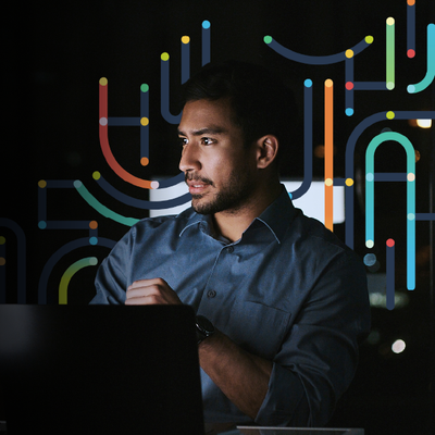 Person using a laptop in front of colorful abstract light patterns, looking to the side.