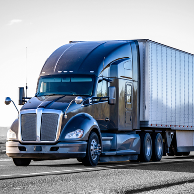 Blue semi-truck with a white trailer driving on a highway