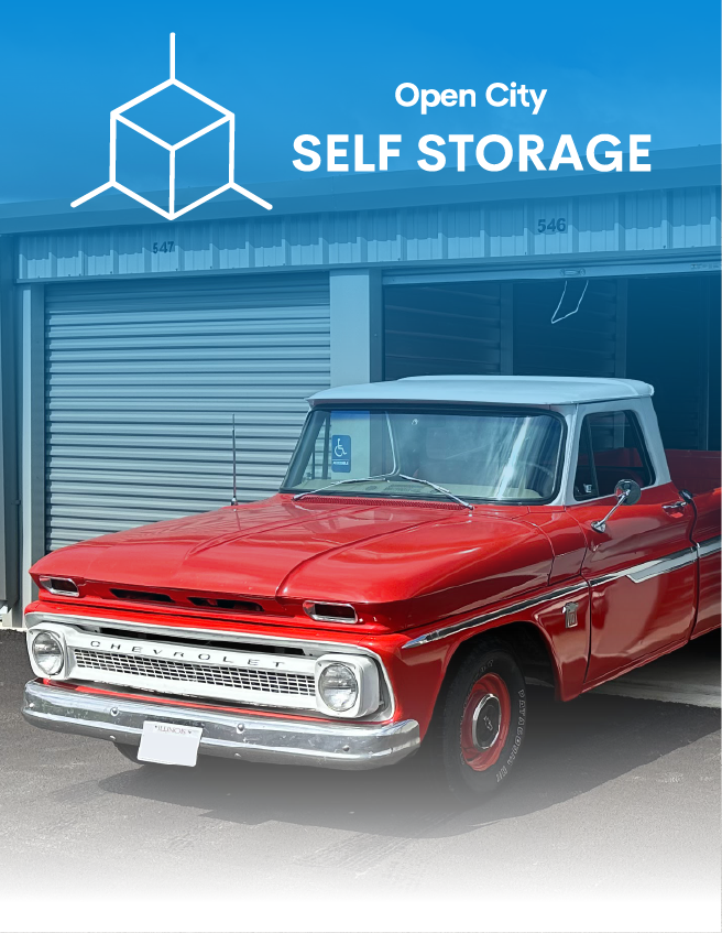 Red classic pickup truck parked outside Open City Self Storage with blue signage