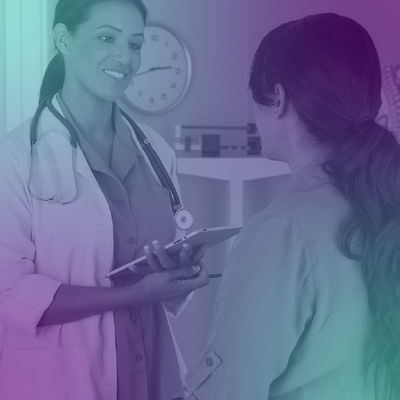 Doctor speaking with a patient in a clinic, holding a clipboard and smiling.