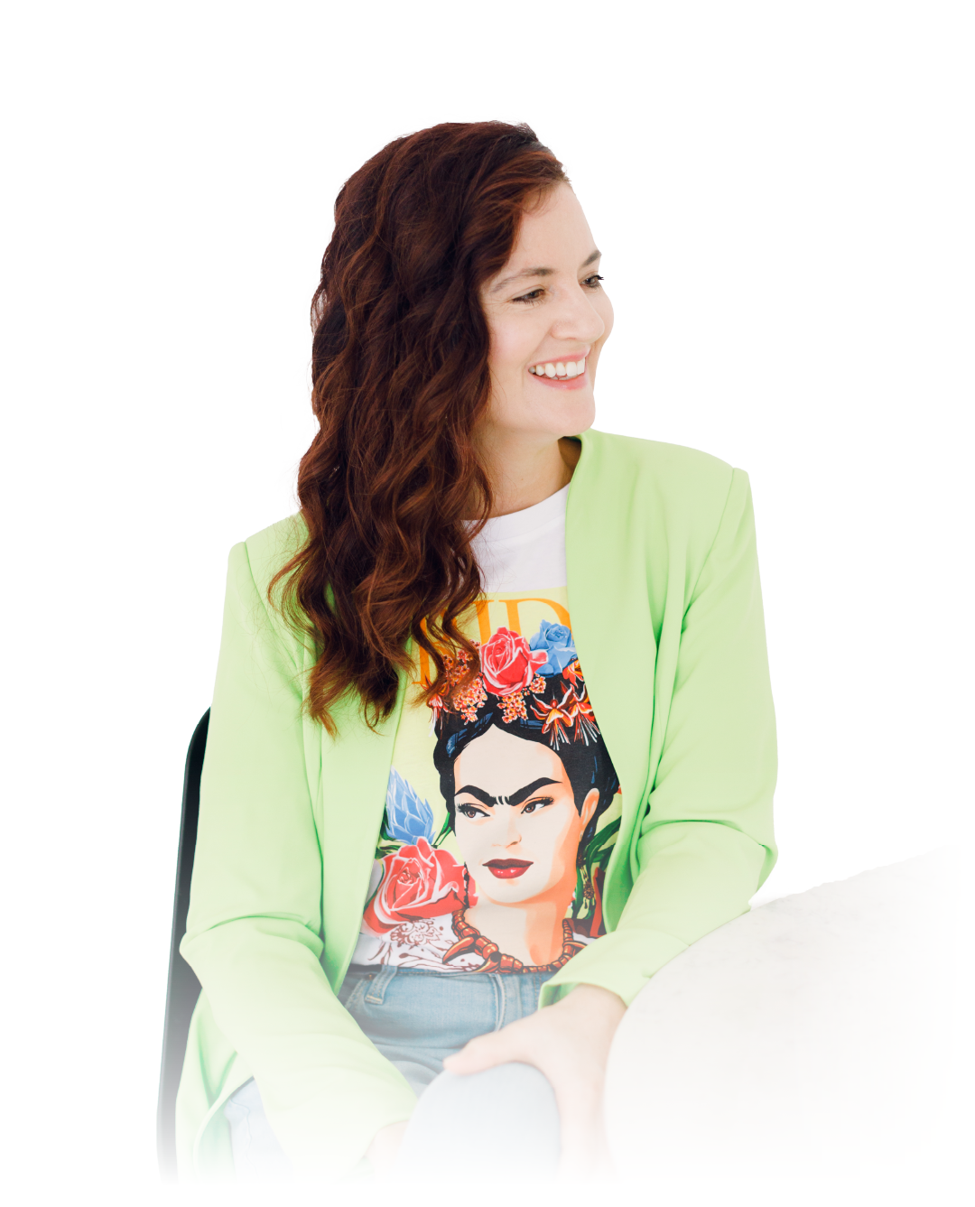 Woman in a light green blazer smiling and looking left, wearing a colorful Frida Kahlo T-shirt.