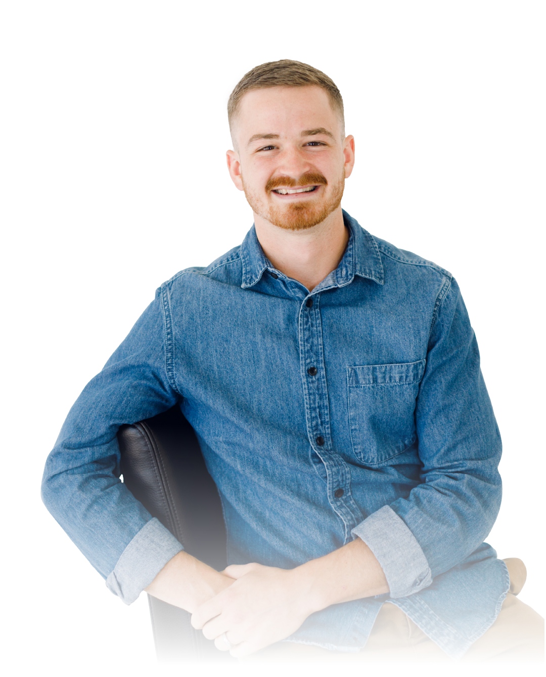 Smiling person in a blue shirt sitting with a laptop against a white background