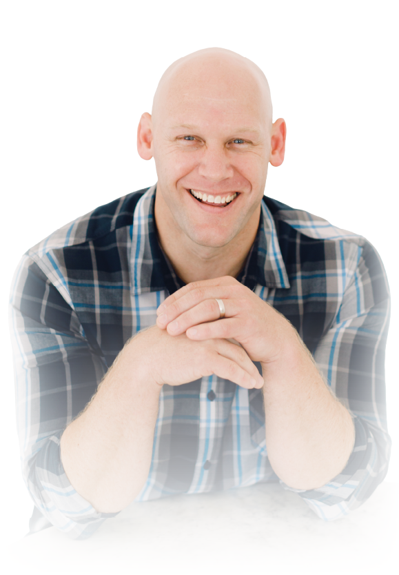 Smiling bald man in plaid shirt leaning forward with hands clasped