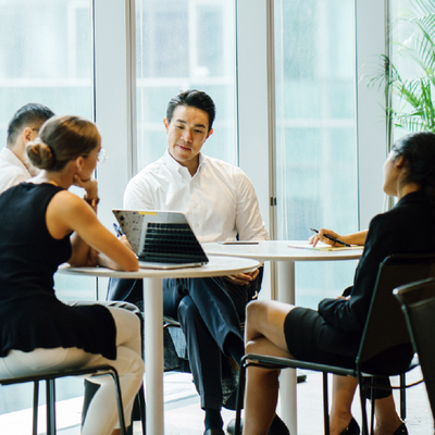Business team in a bright office meeting around a round table with laptops and documents
