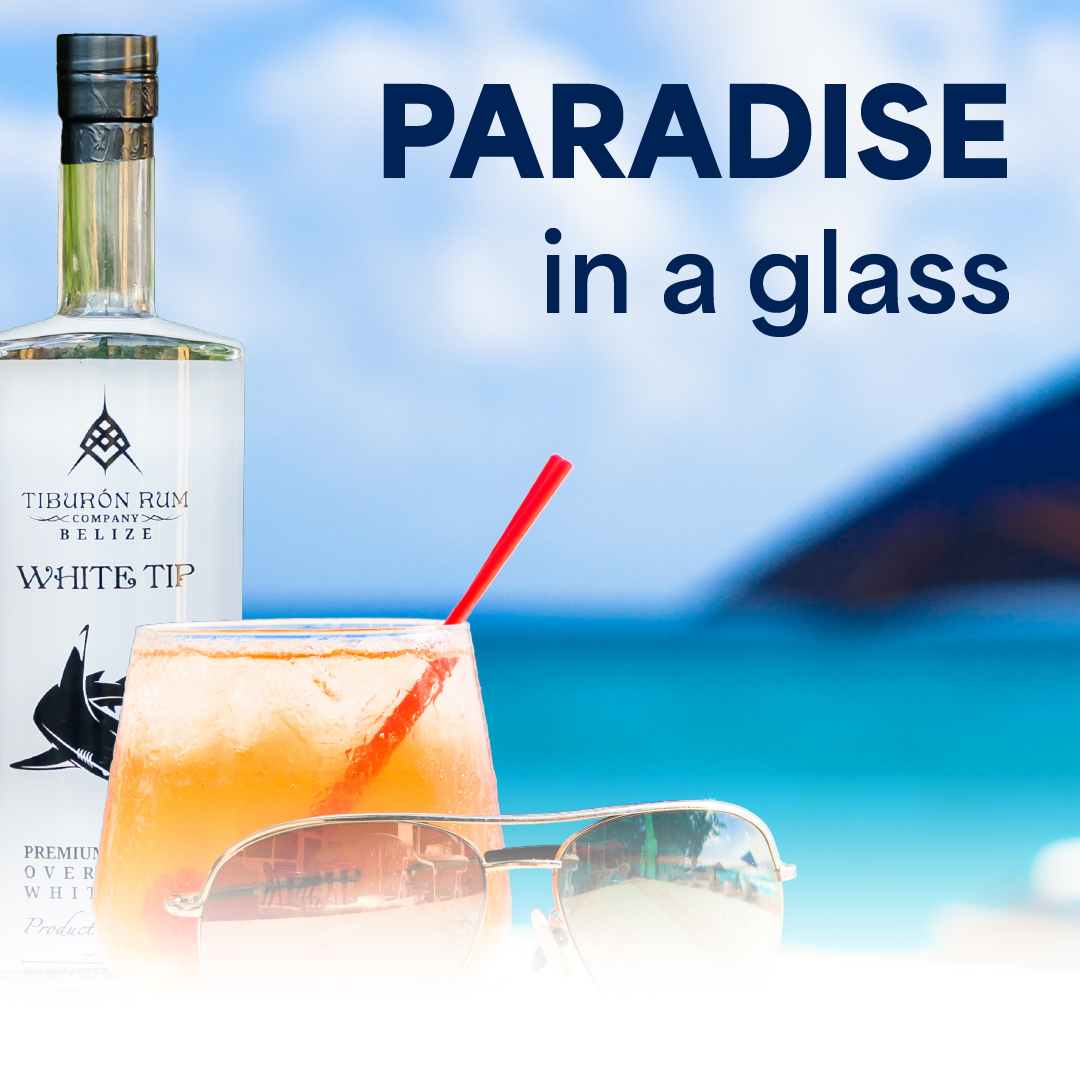 Bottle and cocktail on a beach with text “PARADISE in a glass” and a red arrow pointing to the drink.