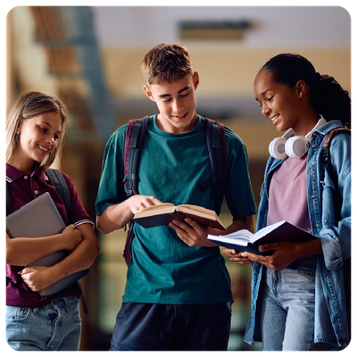 Three students reading books together in a school hallway, smiling and discussing