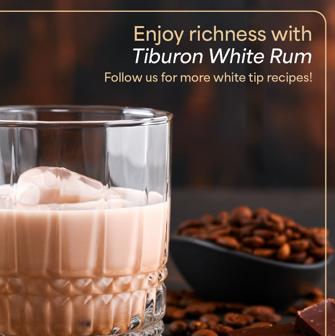 Glass of creamy white rum drink with ice beside coffee beans and a Tiburon White Rum promo text