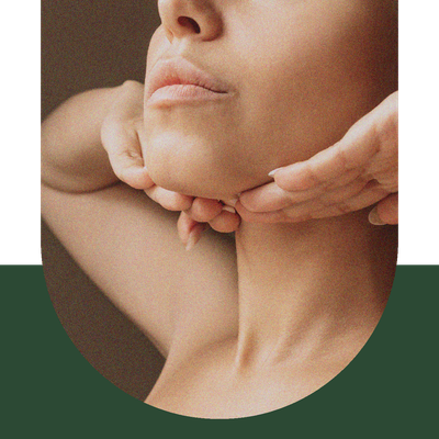 Close-up of a person resting their chin on both hands against a neutral background.