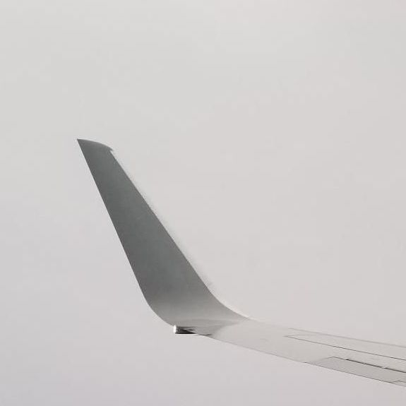 Airplane wingtip against a pale gray sky