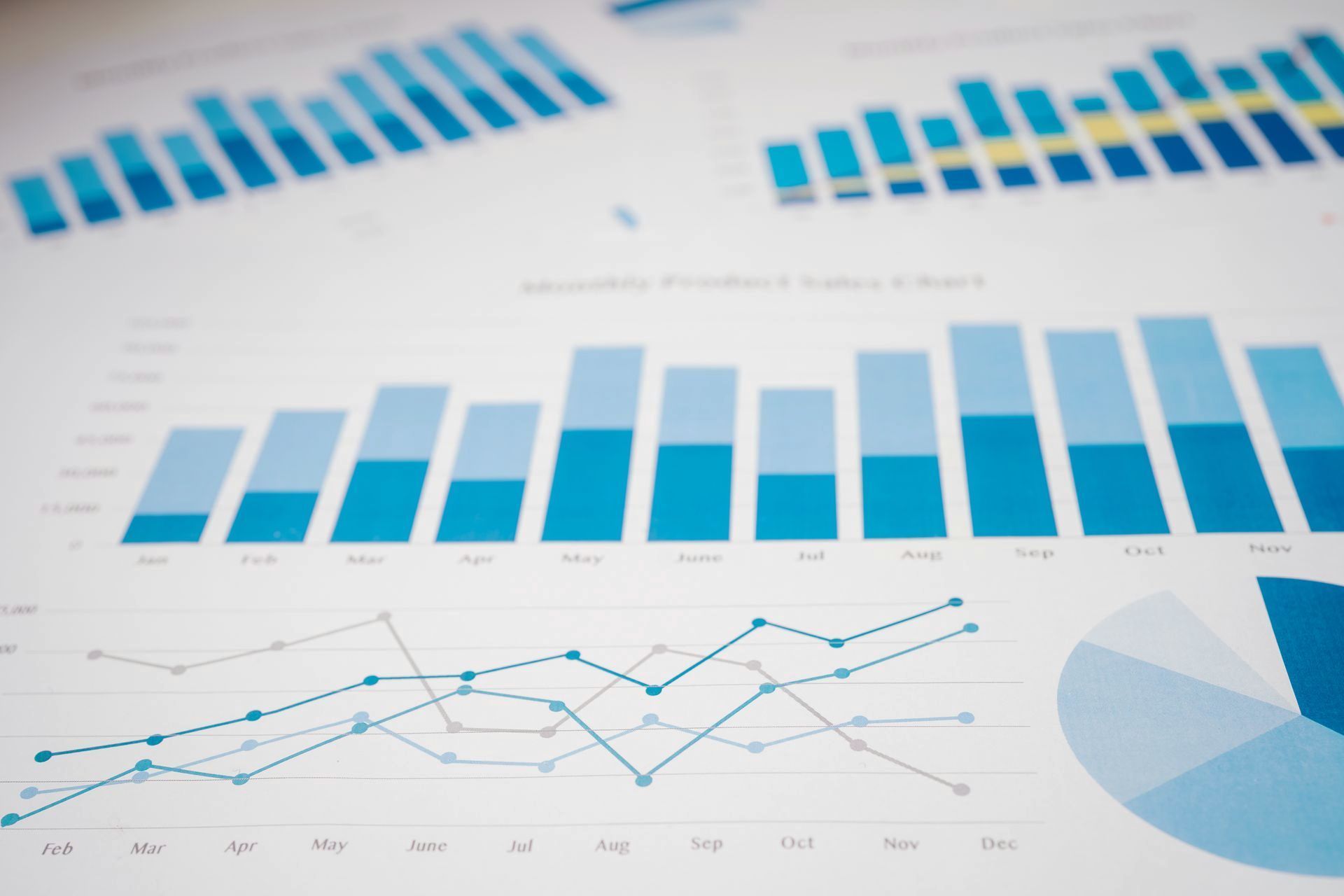 Blue business charts and graphs on a white background, including bar, line, and pie charts.