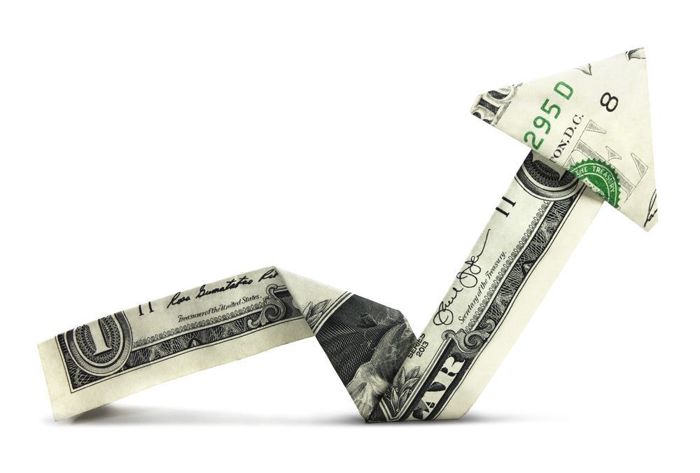 Dollar bills folded into an upward arrow on a white background