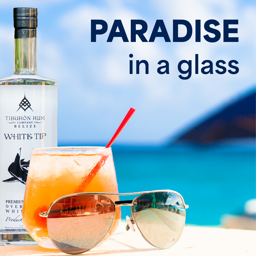 Paradise cocktail with bottle and sunglasses on a beach, with “PARADISE in a glass” text.