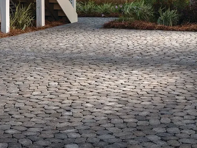 A brick driveway with a staircase in the background