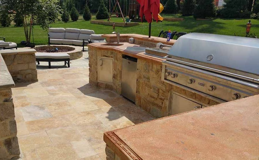 A large outdoor kitchen with a grill and a fire pit.