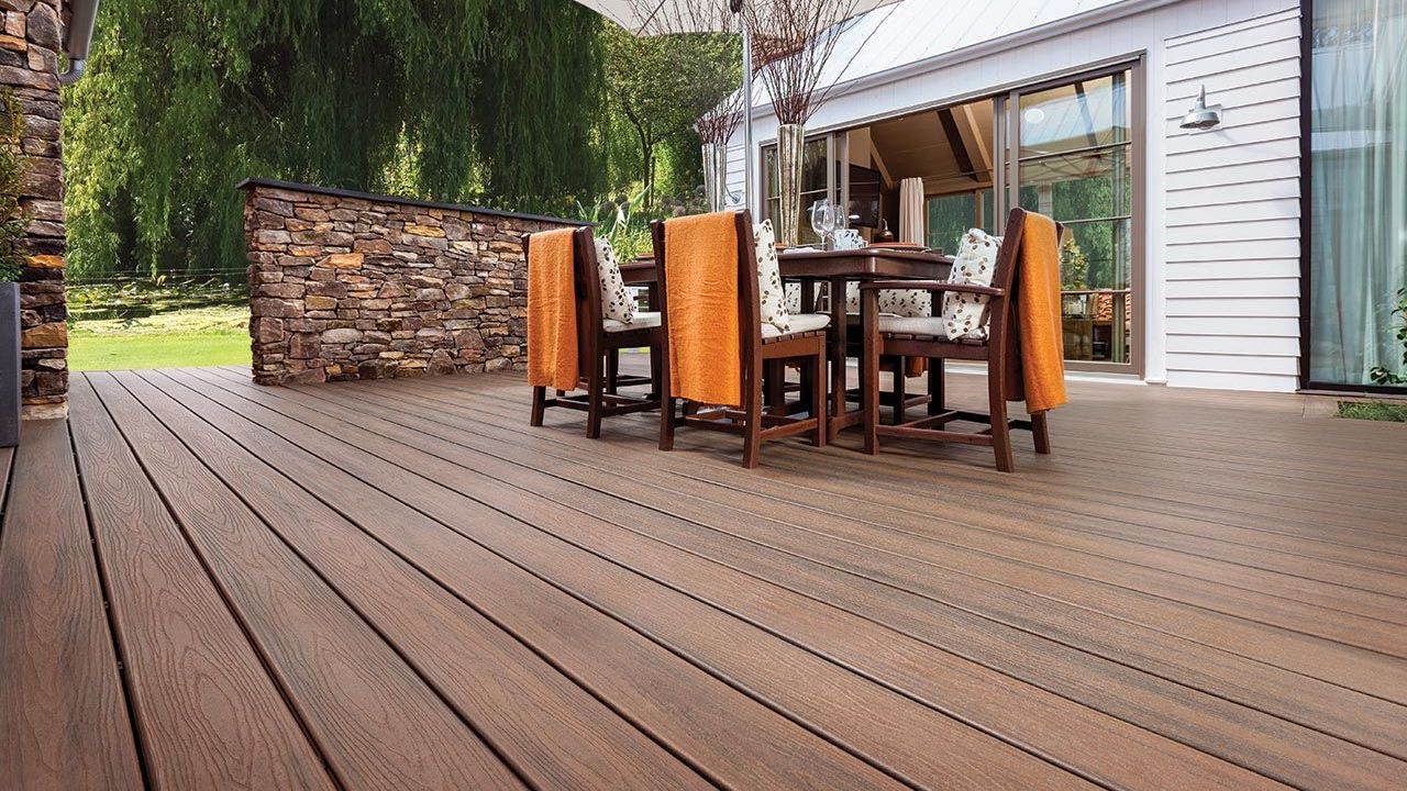 New composite deck with outdoor dining set against a house and stone wall.