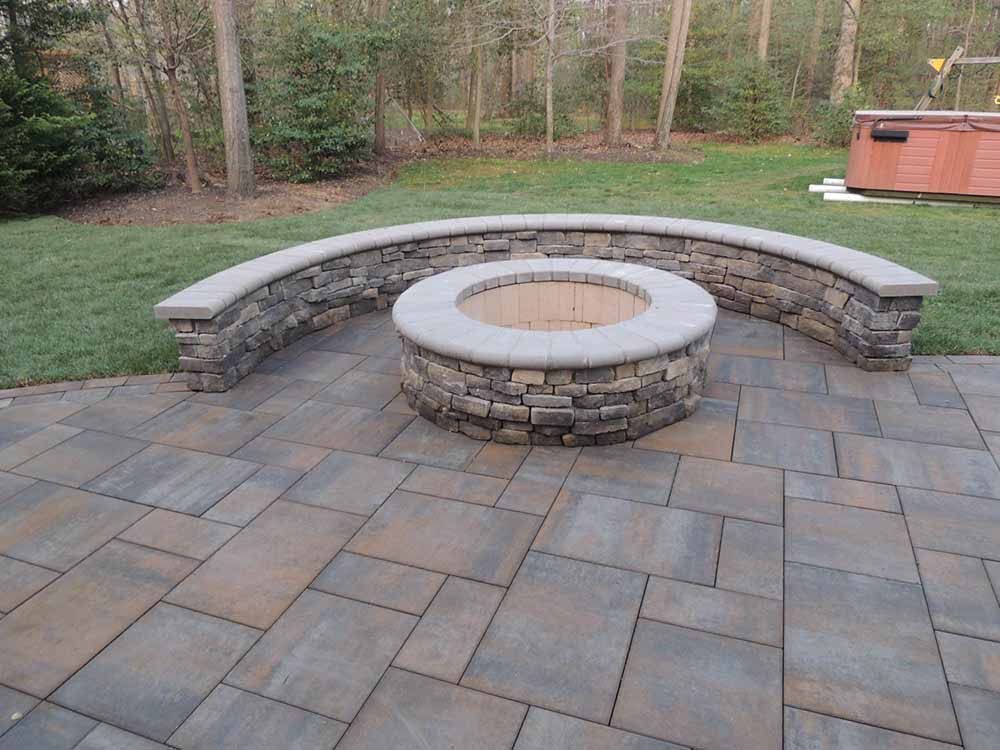 A fire pit is surrounded by a stone wall on a patio by J Gonzalez Construction in Maryland