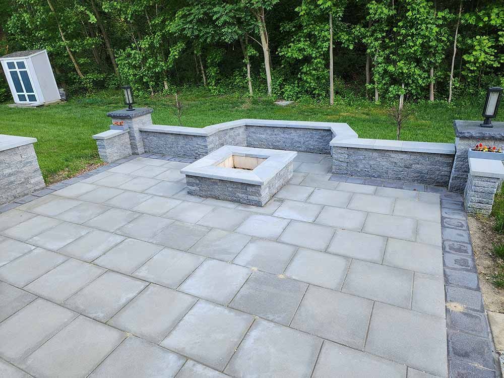 Flag Stone Patio with a Square Outdoor Fireplace Installation and a Sitting Wall in Maryland by J Gonzalez Construction