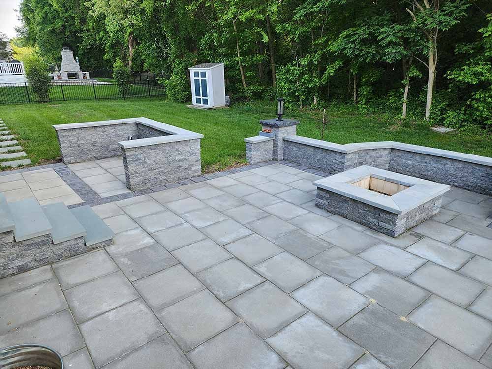 A stone fireplace in a backyard with a fence around it