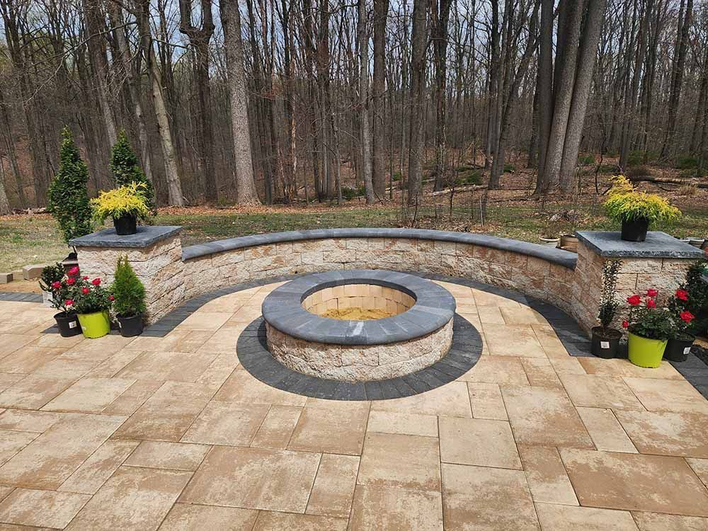 There is a fire pit in the middle of the patio with a sitting wall in Maryland