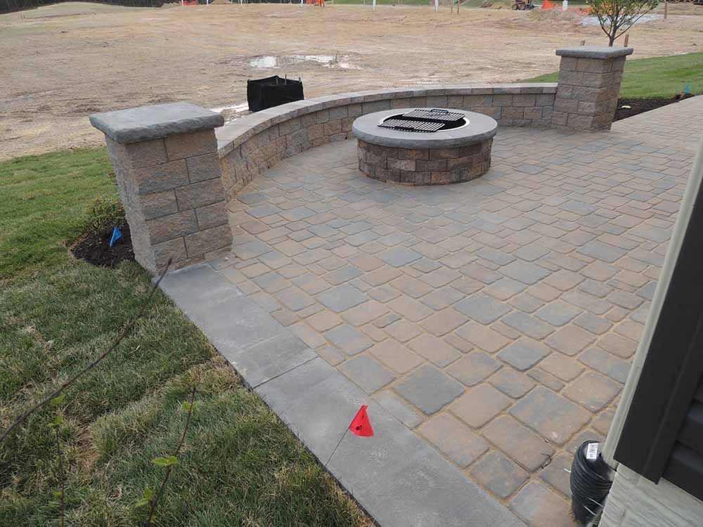 A brick patio with a fire pit in the middle of it