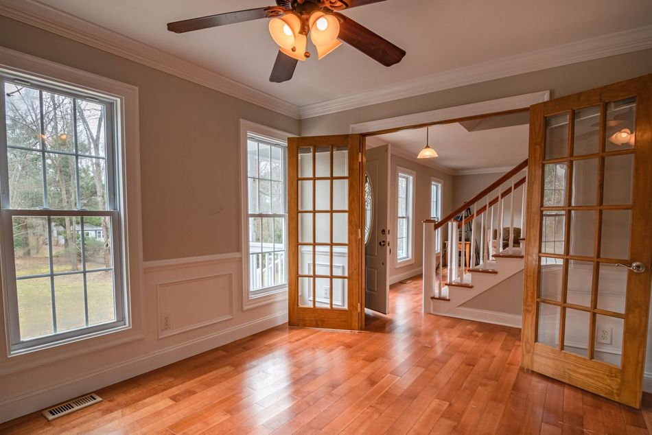 An empty room with hardwood floors and a ceiling fan.
