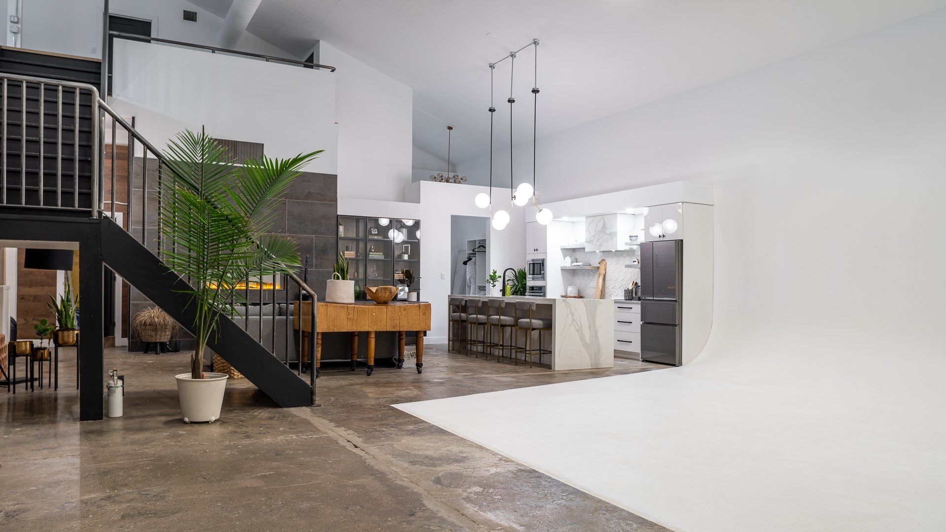 a large room with a staircase leading to the second floor and a kitchen .