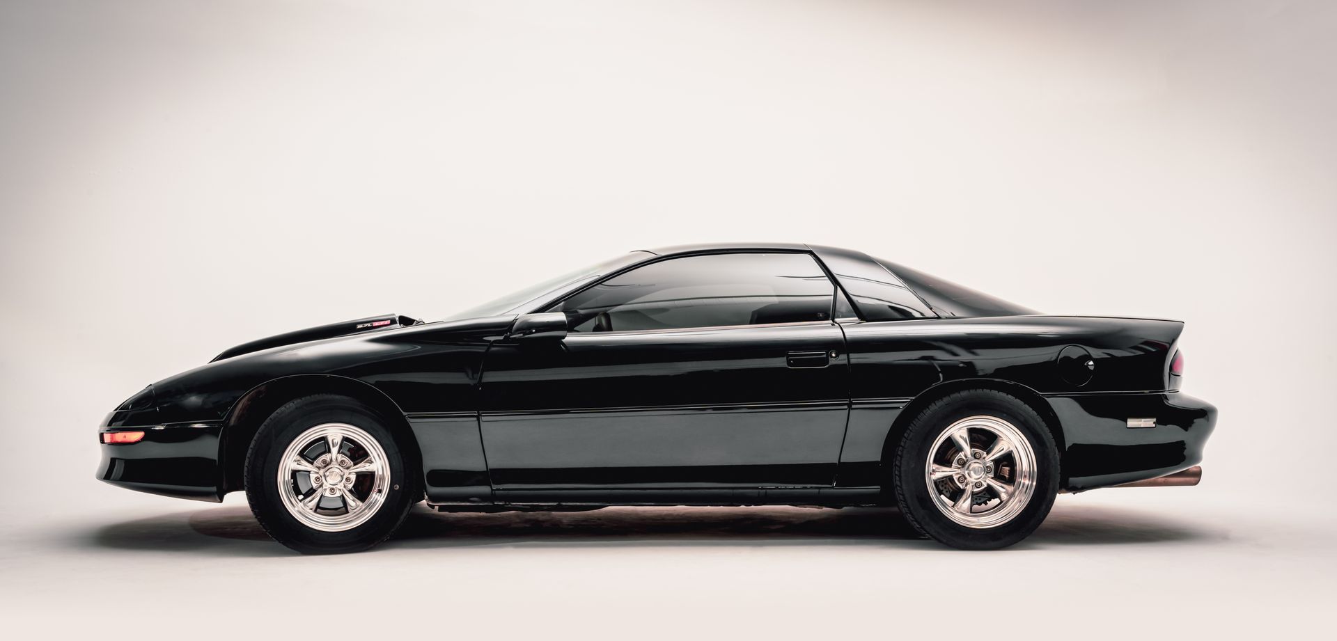 Black sports car, side view, on a white backdrop.