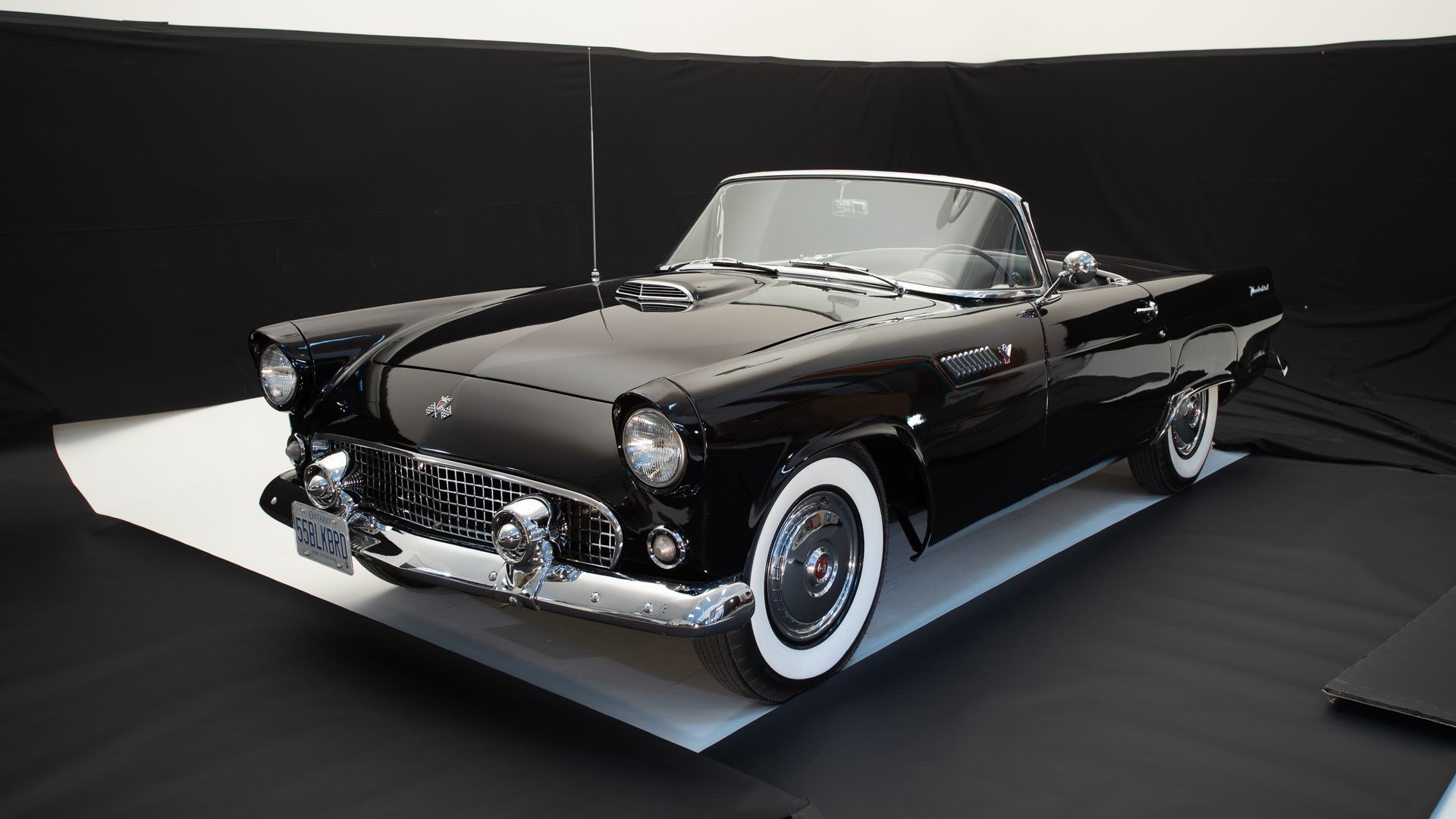 a black car with white tires is parked on a black surface .