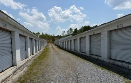 Outdoor drive-up storage aisle with white roll-up doors at Bagby Storage