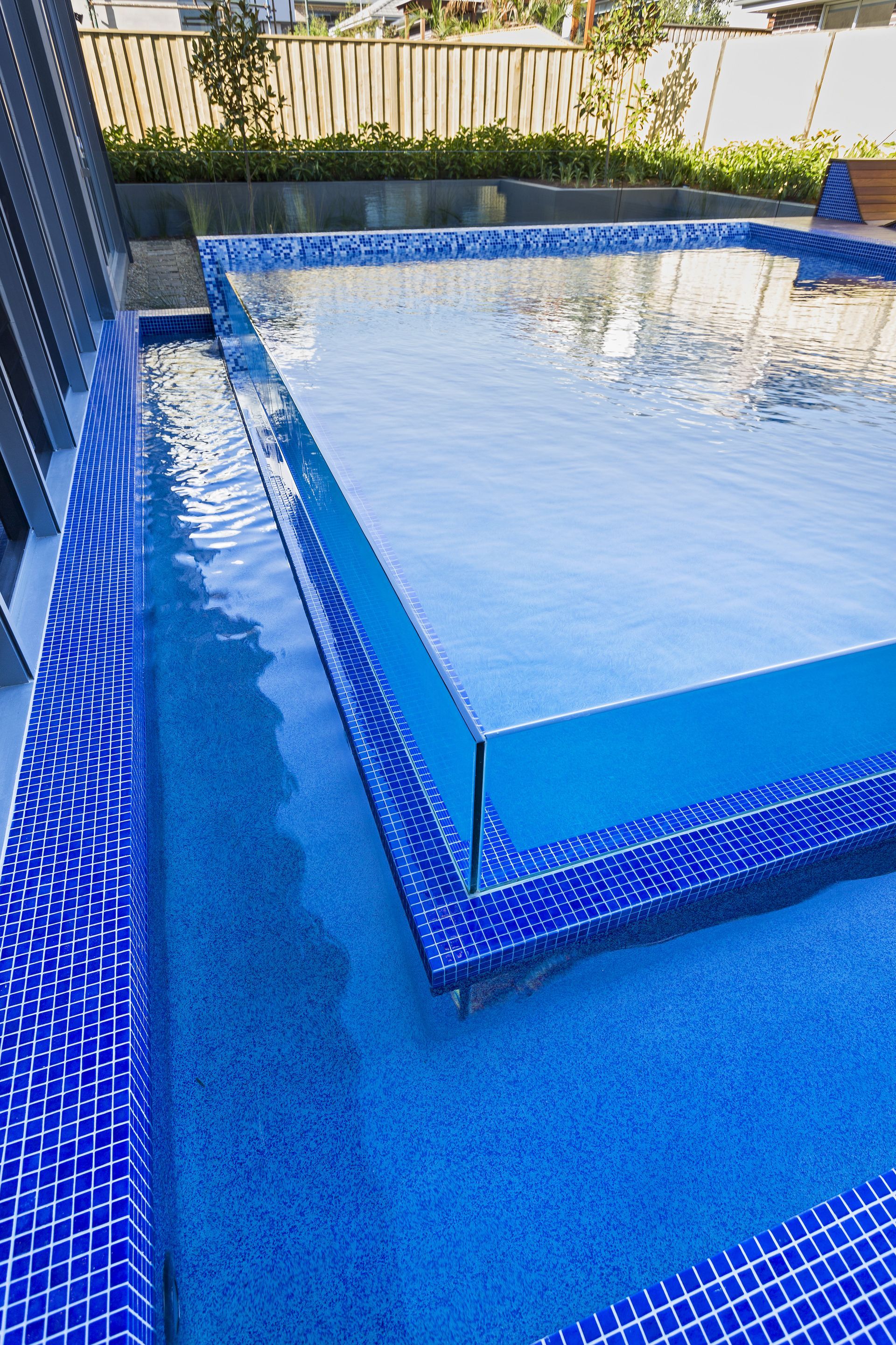 A Large Swimming Pool With Blue Tiles And A Clear Glass Wall — Glass Pool Windows Australia In Old Bar, NSW