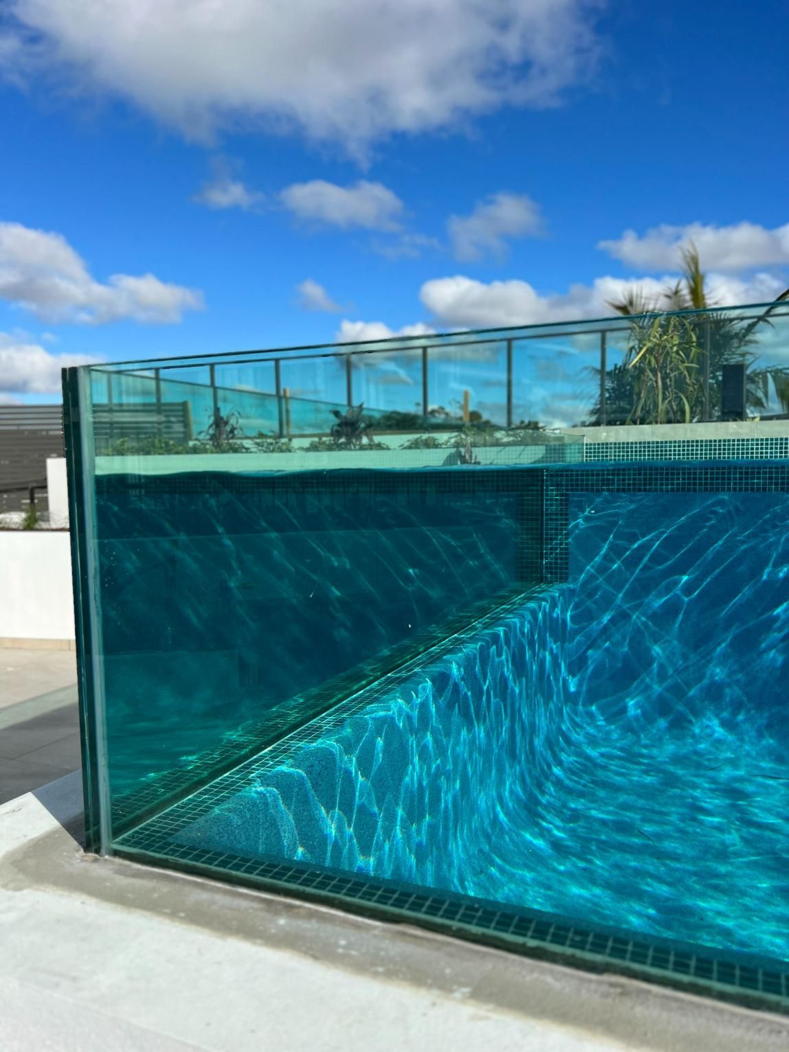 A Swimming Pool With A Clear Glass Fence And A Blue Sky In The Background — Glass Pool Windows Australia In Newcastle, NSW