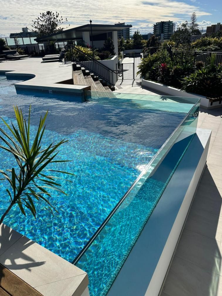 A Large Swimming Pool With A Clear Glass Fence Around It — Glass Pool Windows Australia In Old Bar, NSW