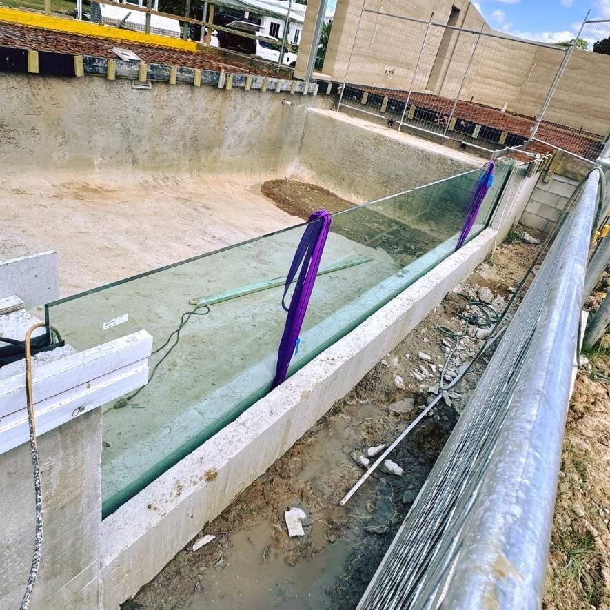 A Swimming Pool Is Being Built With A Glass Fence Around It — Glass Pool Windows Australia In Sunshine Coast, QLD