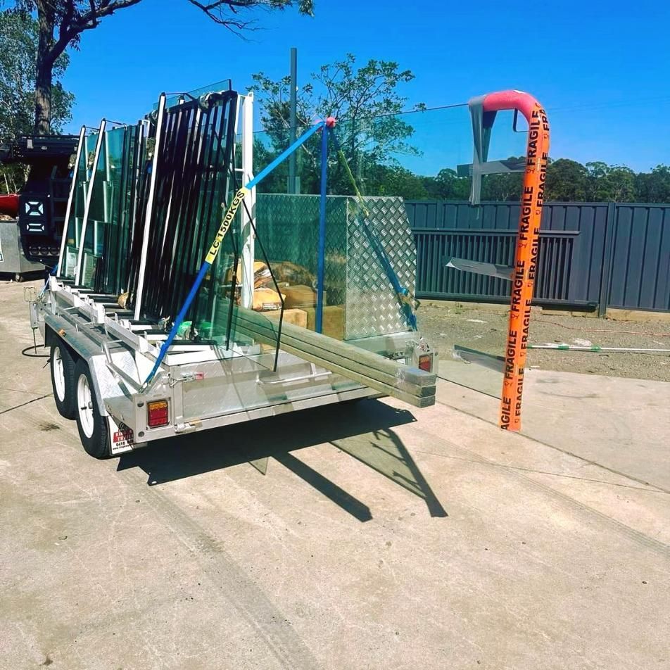 A Trailer Is Loaded With A Lot Of Glass And A Hose — Glass Pool Windows Australia In Wollongong, NSW