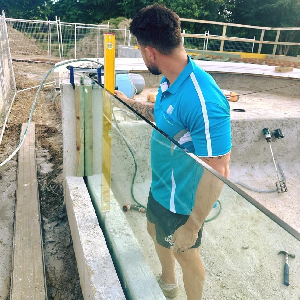 A Man In A Blue Shirt Is Working On A Glass Railing — Glass Pool Windows Australia In Rockhampton, QLD